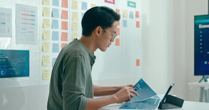 Group of Asian businesspeople work together leads business meeting uses presentation TV with revenue, profit or sale statistics in office. Financial generation z team brainstorm on e-Commerce project.
