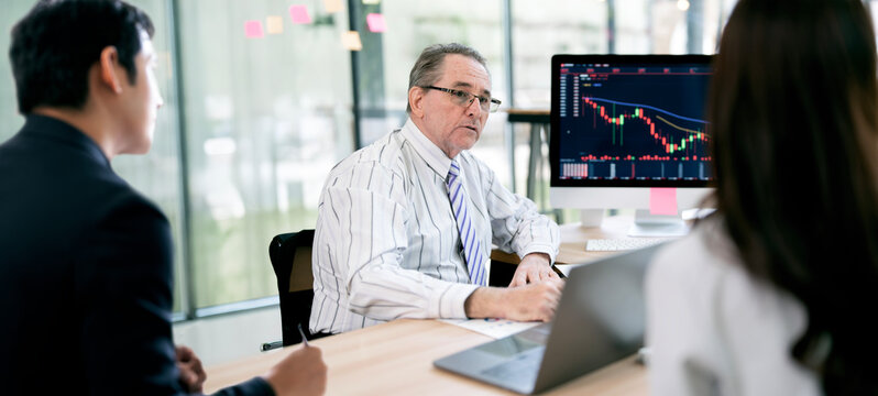 Senior businessman explaining stock market data chart in meeting.