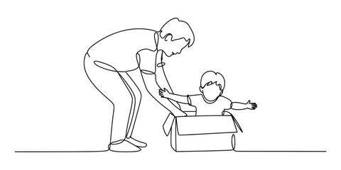 Fototapeta premium Father playing with baby sitting in a cardboard box