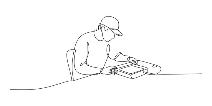 Man wearing a cap working on a laptop at a desk