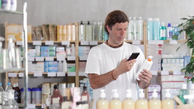 Adult man buyer scanning qr code for sunscreen or tanning product in pharmacy