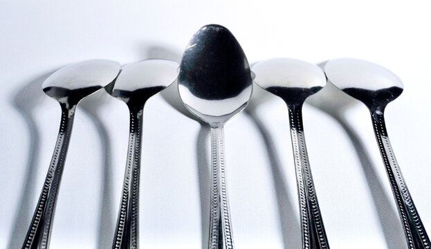 Four upside down silver spoon and one not upside down silver spoon isolated on horizontal background.
