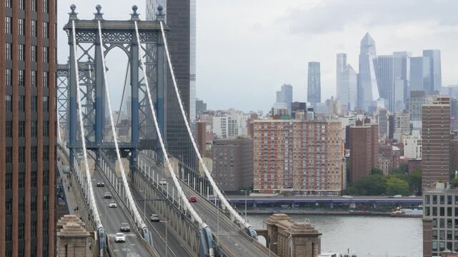 Manhattan bridge from above, rooftop in Brooklyn Dumbo, New York, United States. City traffic on transport bridge aerial view, cars on road. Hudson Yards district skyscrapers, towers on rainy day.