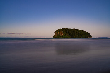 Naklejka premium A solitary island and its reflection in the sea at dusk, New Zealand