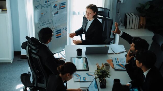 Top view of smart manager project pointing at whiteboard with mind map and financial graph and explain marketing idea while diverse investors listening and analyze stock investment chart. Directorate.