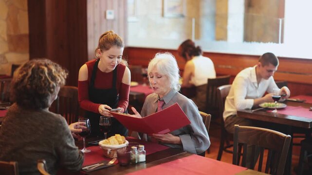 Girl listen to restaurant of customer, write down order items in phone note, record order dish name in mobile application. Waitress of public catering answer customers question