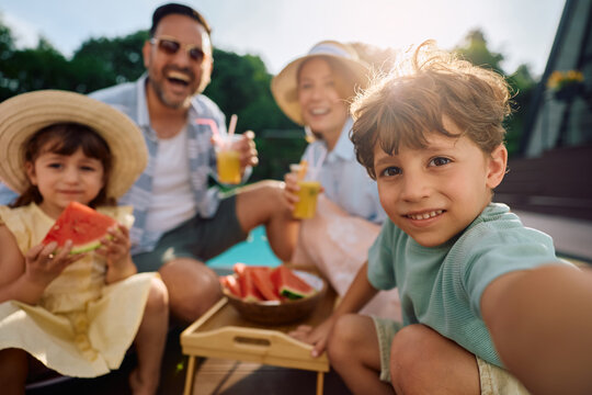 Happy boy taking selfie with his family during summer holiday and looking at camera.