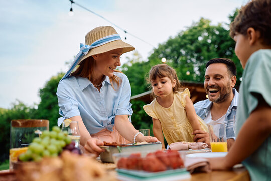 Happy woman serving favorite family dish during lunch on patio.