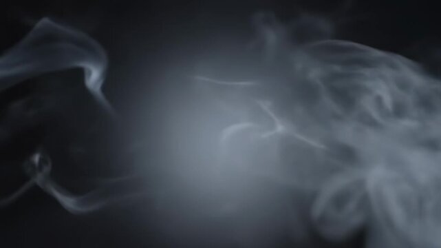 Smoke billowing and swirling in a dark environment, creating a dynamic visual effect with gradual transitions and varying densities of the vaporous substance