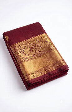 Traditional folded maroon Indian silk saree with gold zari border isolated on a white background