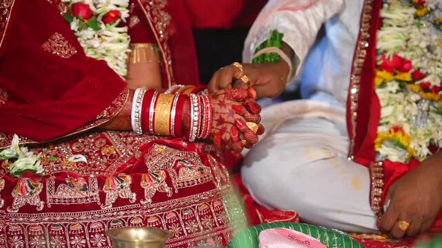 Close-up footage of bride and groom hands participating in traditional Hindu wedding rituals during a marriage ceremony in India. The scene captures sacred customs, ceremonial offerings