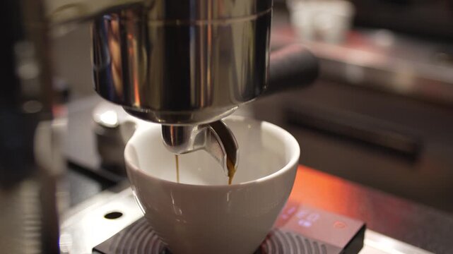 Close-up of artisanal espresso preparation, white cup in modern specialty coffee shop