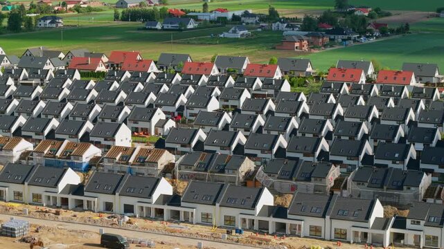 An aerial view of a newly built estate of single-family houses in rows on the outskirts of a large city, real estate market, prices and use of space by developers.
