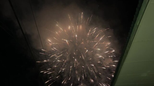 Close-up shot of colorful fireworks exploding and sparkling in the dark night sky. Concept of celebration, holiday, and festival event. Real time.