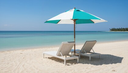 Fototapeta premium Serene Beach Escape: Two empty lounge chairs and a striped umbrella await under a clear blue sky on a tranquil white sand beach, overlooking the calm, turquoise ocean and a distant tropical coastline.