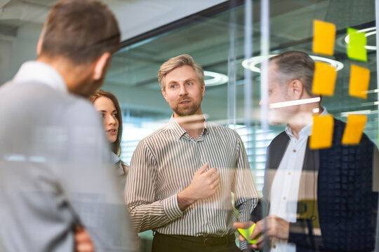 Creative group or business people planning innovation with sticky notes on glass wall.