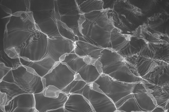 Abstract black and white water ripple background with caustic light reflections.