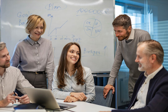 Successful businesspeople working in a coworking space working with laptop discussing strategy and business plan in modern office.