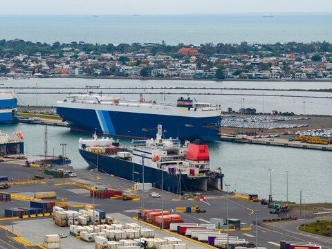 Aerial view of ships at port behind rows of trucks and containers