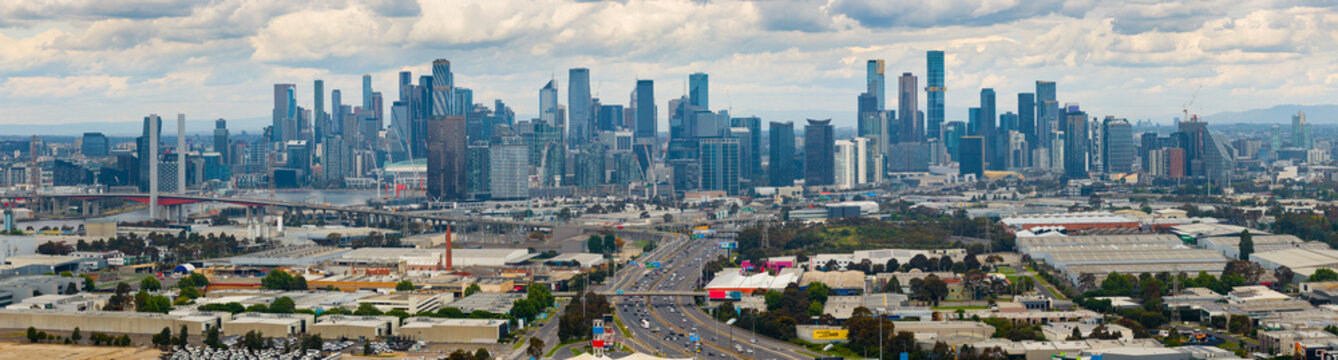 Aerial panorama of a wide city skyline behind freeways and industrial areas
