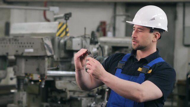 Skilled machinist using caliper to inspect precision metal component in manufacturing facility. Quality control and dimensional measurement in industrial production.