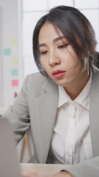 Vertical Screen : Young Asian businesswoman with laptop overworked tired burnout syndrome at office. Exhausted lady with sleeply eye at workplace, Girl not enjoy unhappy with work, Work mental health.
