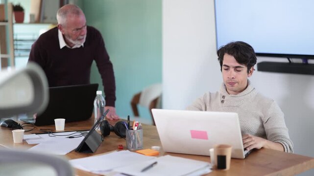 Senior man head of department shouts at guy subordinate who is working at laptop. Reprimand from superiors, hardships of internships, complaints and dissatisfaction of superiors.