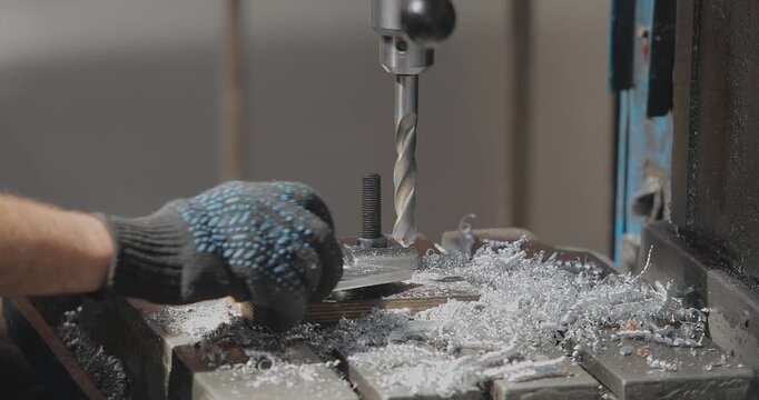 Worker drills a hole in an aluminum part. RIB boat manufacturing, worker makes a hole