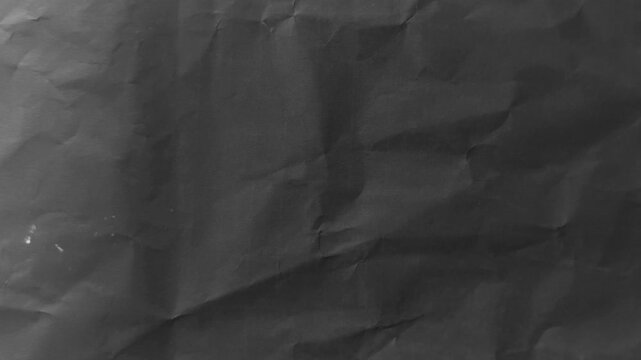 Stop motion animation of dark grey crumpled paper texture background with rough creases and folded grunge pattern, 4k video