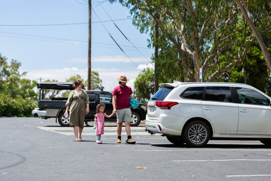 People walking to car in carpark on bright summers day after a picnic