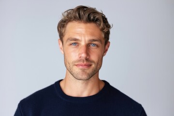Obraz premium The man with blue eyes and subtle smile wearing navy sweater in studio portrait