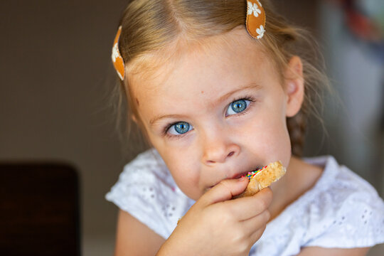 Child with blue eyes eating fairy bread slice