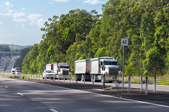 Pair of semi-trailer trucks traveling on road transporting goods