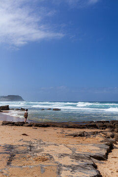 Beach scene with distant teen watching the waves roll in