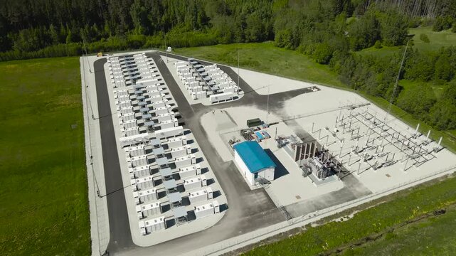 Modern battery energy storage system station using lithium ion technology to store electricity generated by renewable sources, surrounded by lush green forest on a sunny day