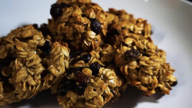 Freshly baked homemade oatmeal raisin cookies stacked on a white plate, showcasing their golden brown texture and sweet ingredients in a detailed close up view of the delicious dessert