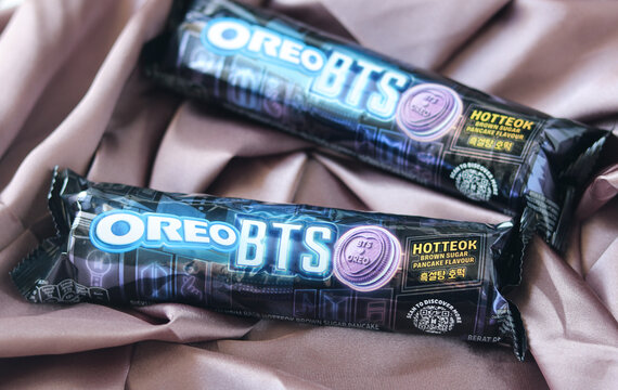 Tangerang, Indonesia - June 7, 2026: Two limited edition Oreo BTS collaboration snack wrapper packs are displayed on a reflective purple cloth.