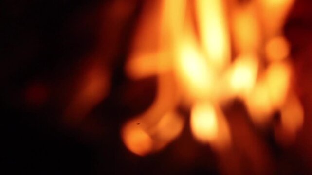 Soft-focus image of glowing orange and yellow flames creating an abstract firelight background. The intentionally blurred effect produces a warm, atmospheric scene ideal for concepts of heat, energy, 
