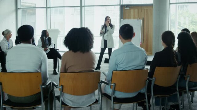 A professional speaker leads an engaged group of colleagues during a corporate training session. Attendees listen intently, fostering communication and collaboration in a business workshop setting.