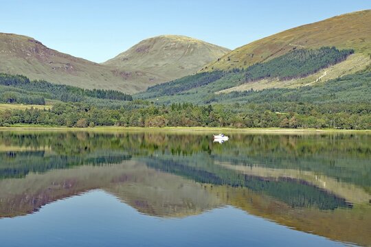 A quiet spur of an estuary with reflections of surrounding mountains and forests on a clear day, Highlands, Fort William, Scotland, Great Britain