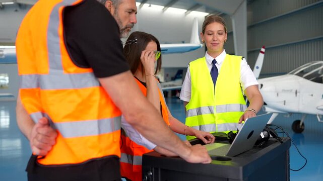 Female pilot instructor training aviation technicians in an aircraft hangar