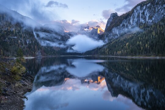 The Vordere Gosausee lake in autumn with a view of the Dachstein mountain range. The Gosaukamm on the right. Blue sky and clouds. In the evening at sunset. Reflection. Vorderer Gosausee, Gosau, Gosau valley, Salzkammergut, Upper Austria, Austria