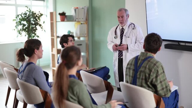 Male doctor speaks to students. Qualified doctor conducts medical courses for construction workers. High quality 4k footage