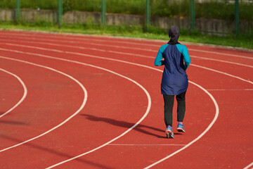Fototapeta premium Muslim Woman Jogging on Outdoor Running Track in Hijab and Modest Sportswear for Fitness