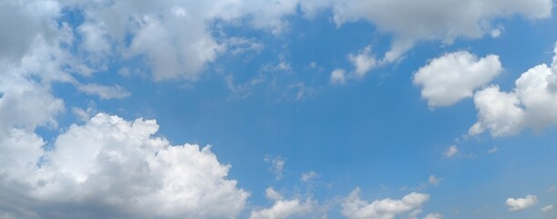 Panoramic blue sky filled with bright white cumulus clouds creating a peaceful natural atmosphere, ideal for weather concepts, seasonal backgrounds, travel themes, and nature inspired designs. © Entas