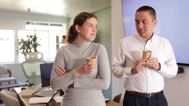 Two office workers drink coffee and chat during a work break. High quality 4k footage