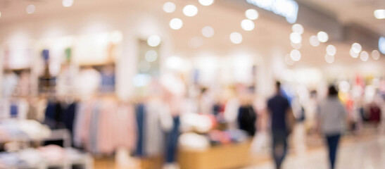 Obraz premium Blurred background of a retail store showcasing clothing racks and shoppers, creating a vibrant shopping atmosphere.