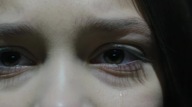 Camera closing revealing bare-shouldered model forming tear and smudging makeup in studio with LED