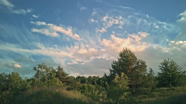Beautiful dramatic clouds timelapse evening sky forest edge.Ukraine. Fast moving colorful cumulus clouds sunset golden hour. Majestic nature scenery, cinematic countryside background, weather changing