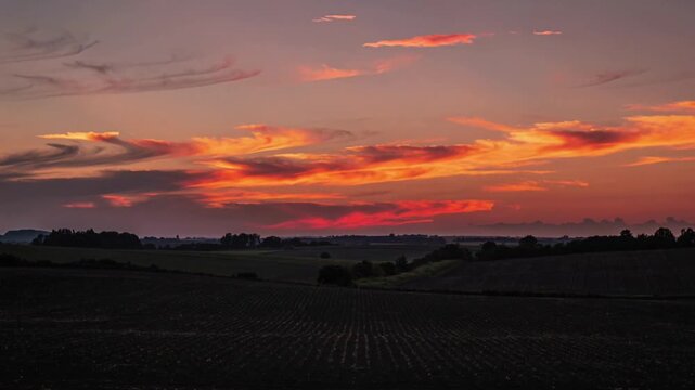 Showing sunset shifting over rural horizon with dusk deepening, revealing tilled furrows and hedge